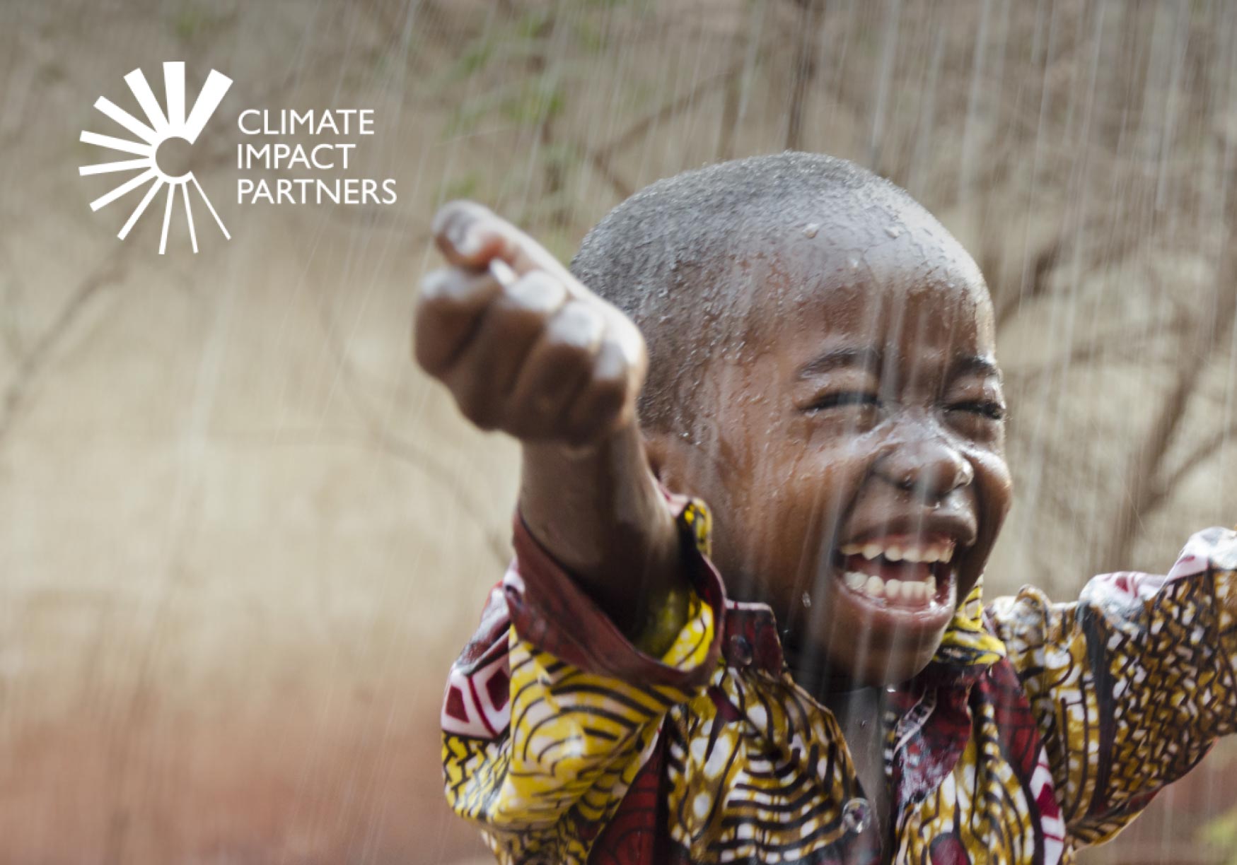 Child in colourful clothing playing under a shower