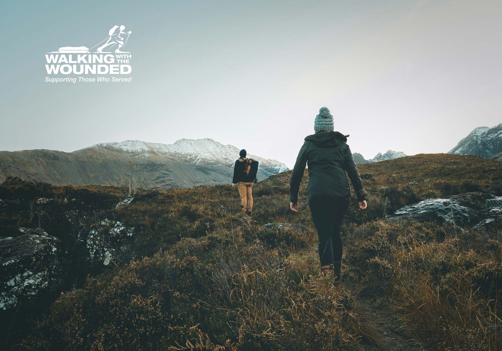 Two people hiking across mountain landscape.